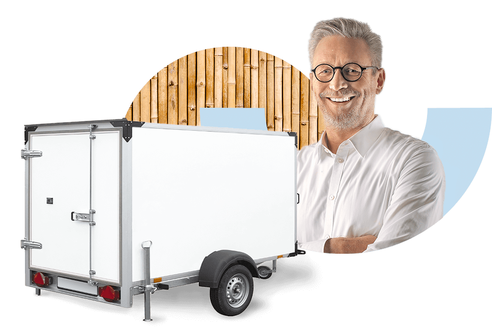 Lachender Mann neben einem weißen geschlossenen Autotransportanhänger