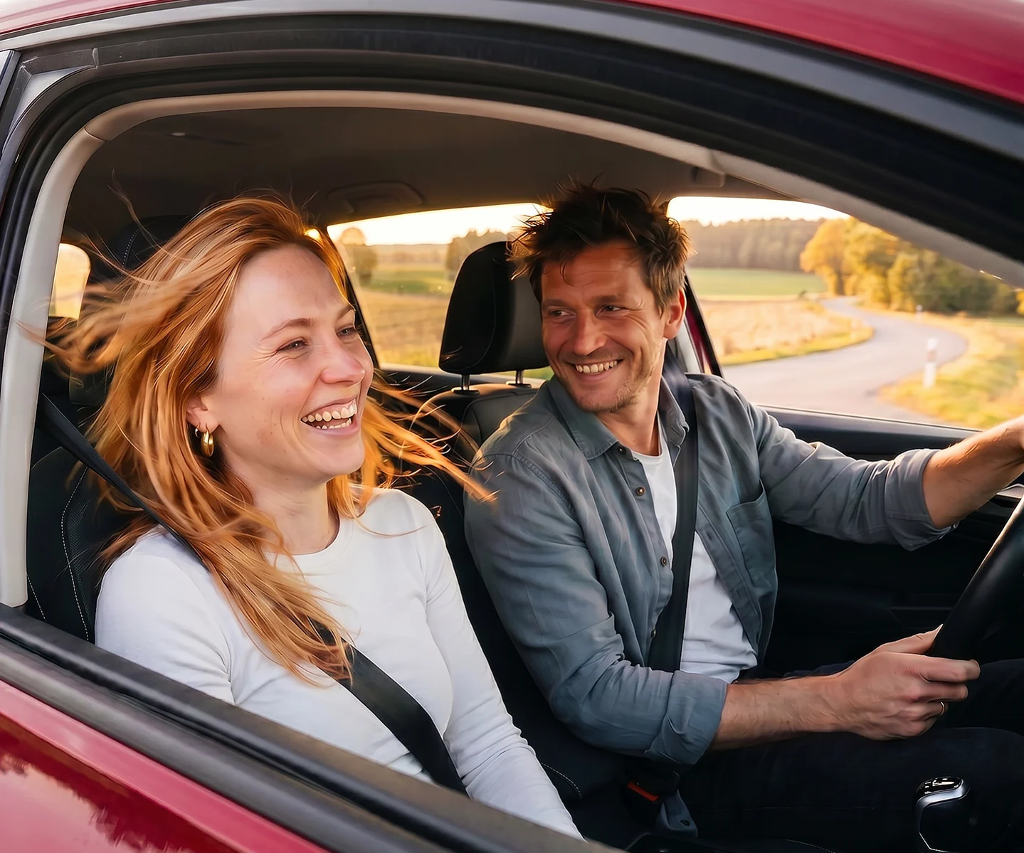 Ein junges Paar sitzt im Auto und lacht | DA Direkt Autoversicherung