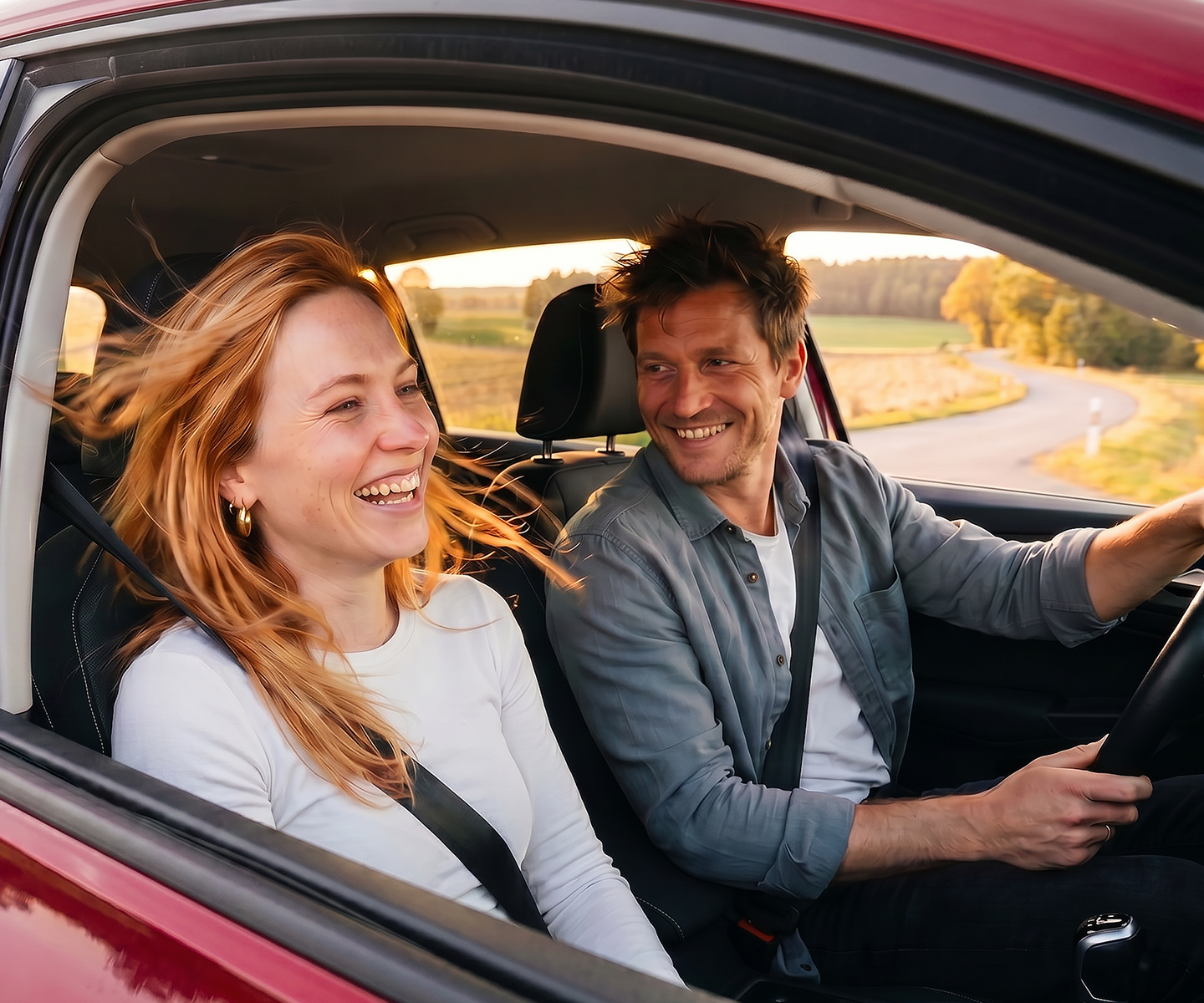 Ein junges Paar sitzt im Auto und lacht | DA Direkt Autoversicherung