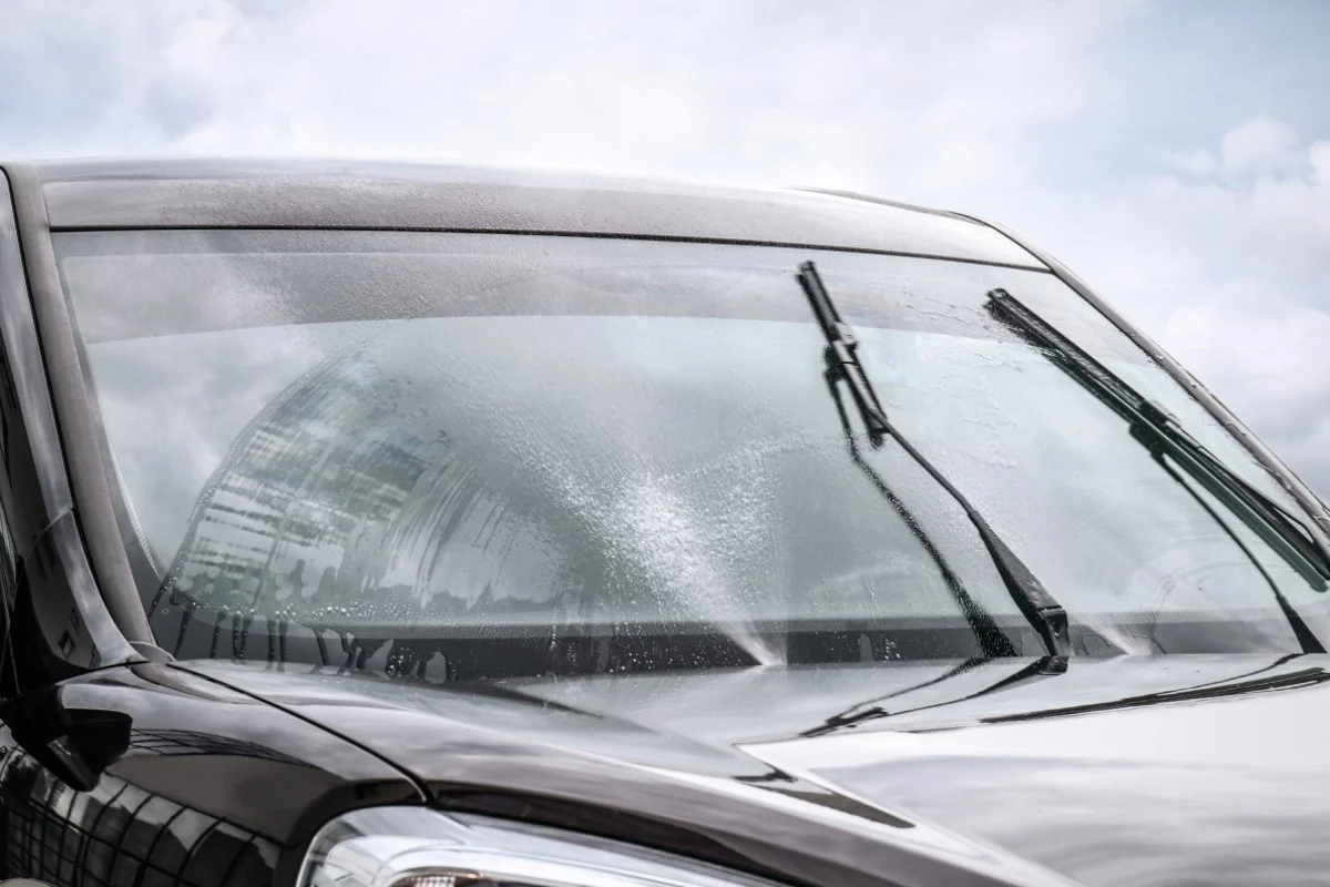 Scheibenwischwasser sprüht durch die Düse auf die Windschutzscheibe eines Autos