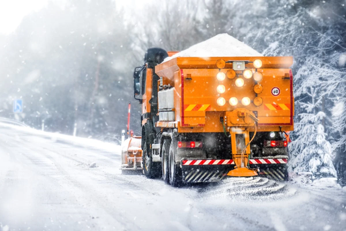 Winterdienst im Einsatz Schneeräumfahrzeug streut winterlich zugeschneite Straße