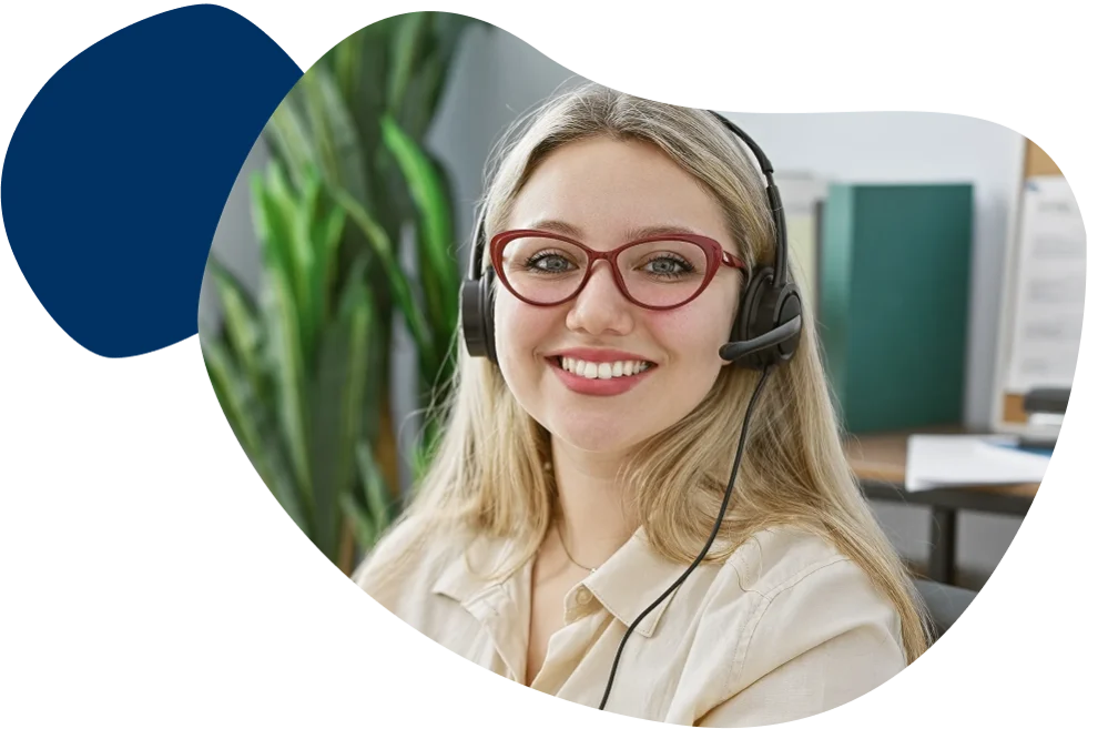 Frau sitzt im Büro mit einem Headset und lächelt freundlich.