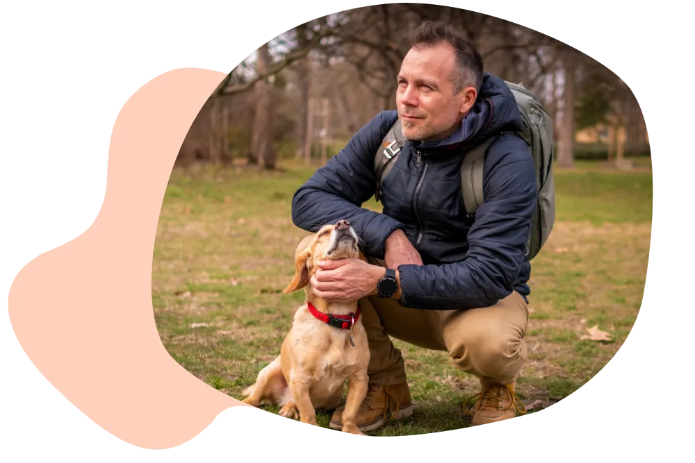 Mann und Hund sitzen auf einer Wiese.