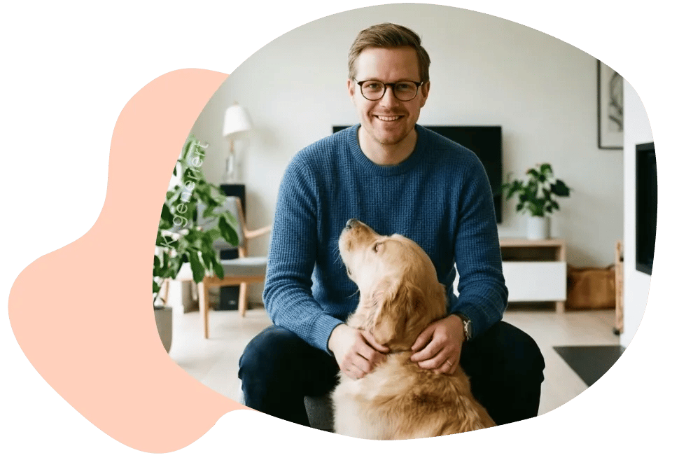 Mann sitzt mit Hund im Wohnzimmer.