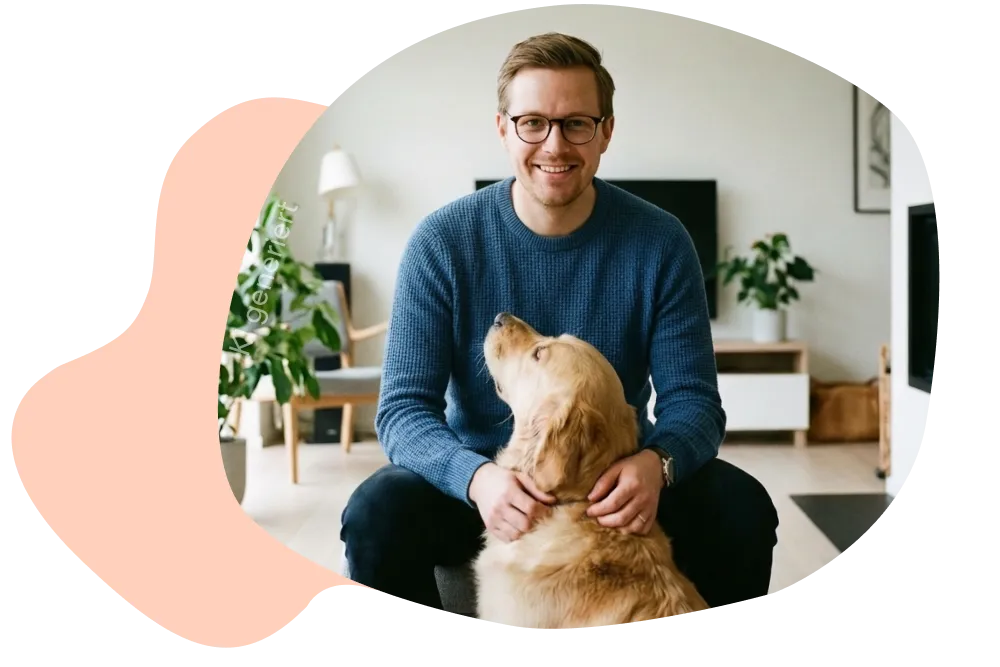 Mann sitzt mit Hund im Wohnzimmer.