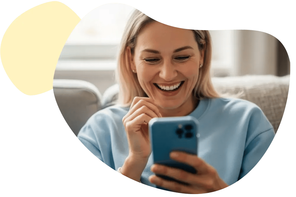 Lachende Frau tippt lächelnd auf ihrem Smartphone